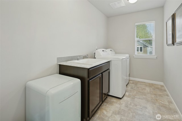 laundry area with cabinet space, baseboards, washer and clothes dryer, and a sink