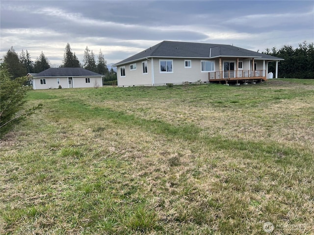 rear view of property with crawl space, a deck, and a yard