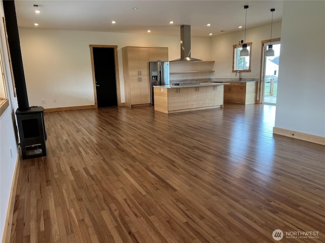 kitchen featuring dark wood-style floors, open floor plan, a wood stove, a kitchen island, and extractor fan