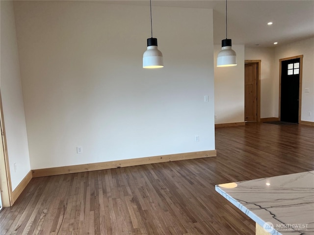 spare room with baseboards, wood finished floors, and recessed lighting