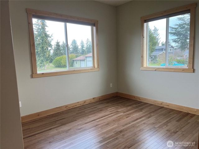 unfurnished room with hardwood / wood-style floors and baseboards