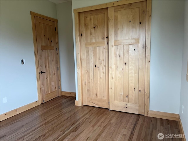 unfurnished bedroom with a closet, baseboards, and wood finished floors