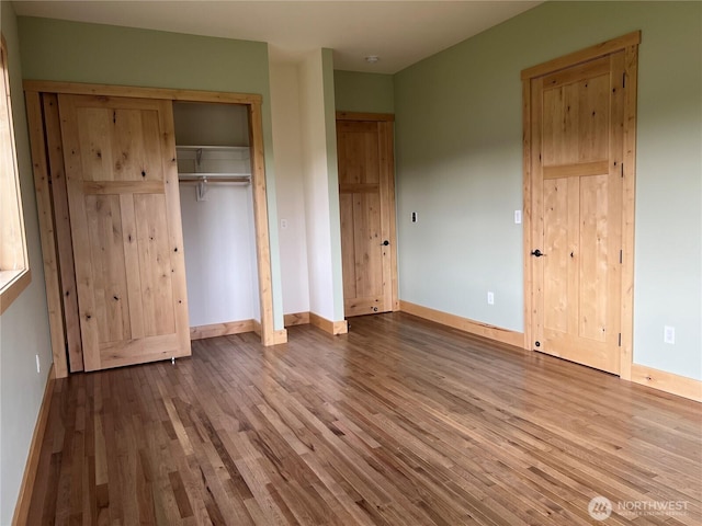 unfurnished bedroom with a closet, wood finished floors, and baseboards