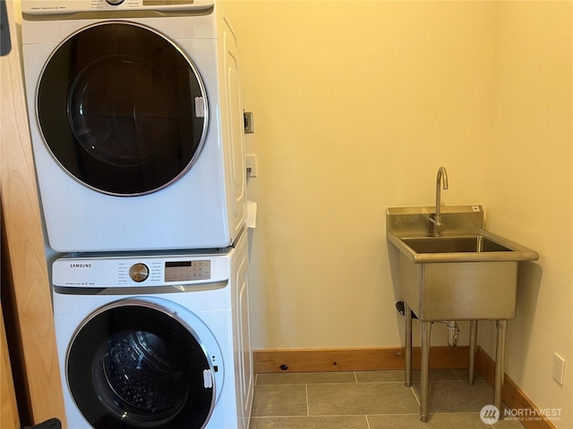 washroom featuring stacked washer and dryer, tile patterned flooring, laundry area, and baseboards