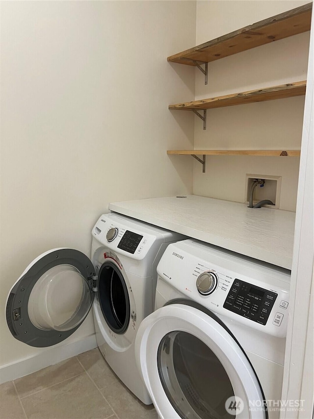 laundry room with laundry area, light tile patterned flooring, washing machine and dryer, and baseboards