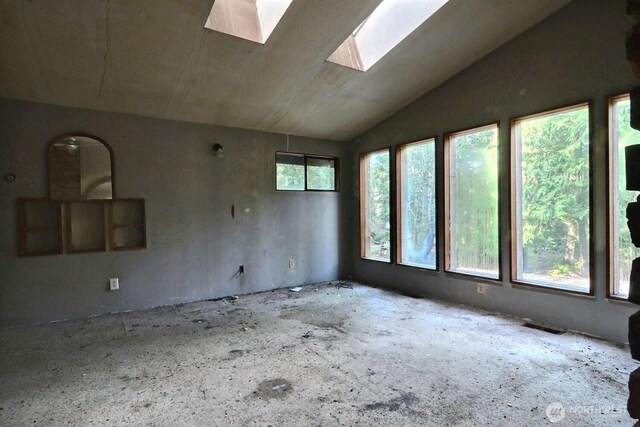unfurnished room with vaulted ceiling with skylight and a wealth of natural light