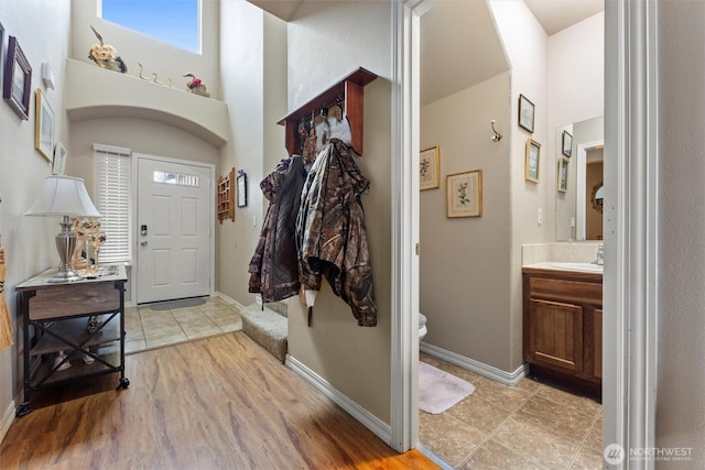 entryway featuring light wood-type flooring, a high ceiling, and baseboards