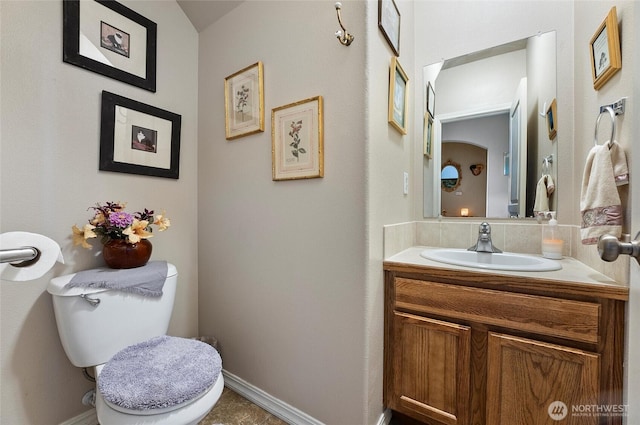 half bath with vanity, toilet, and baseboards