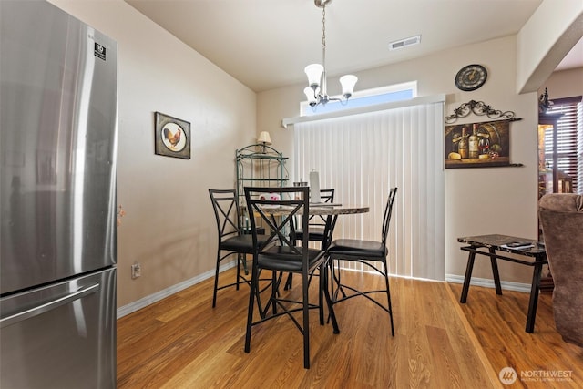 dining space featuring arched walkways, wood finished floors, visible vents, baseboards, and an inviting chandelier