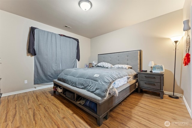 bedroom with baseboards, visible vents, and light wood-style floors