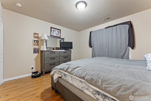 bedroom with light wood-style flooring, visible vents, and baseboards