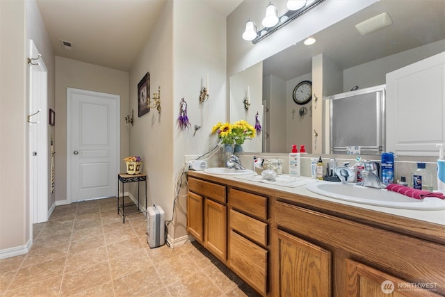 bathroom featuring double vanity, a stall shower, a sink, and visible vents