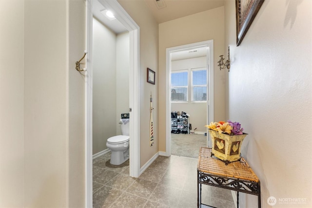 hall featuring visible vents and baseboards