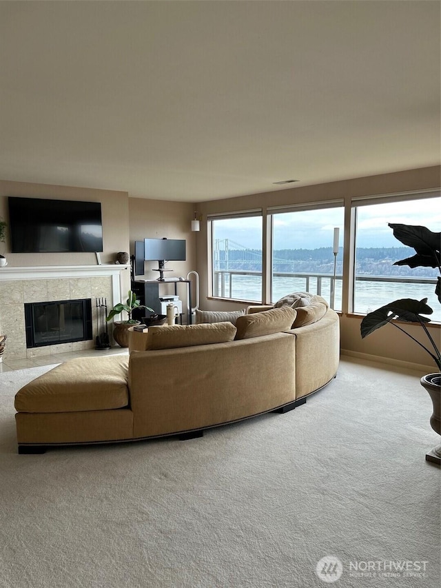 living room featuring visible vents, a tiled fireplace, and carpet flooring