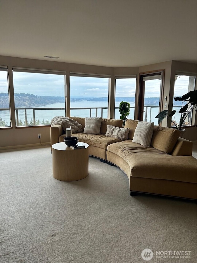 living room featuring a water view, a healthy amount of sunlight, visible vents, and carpet flooring