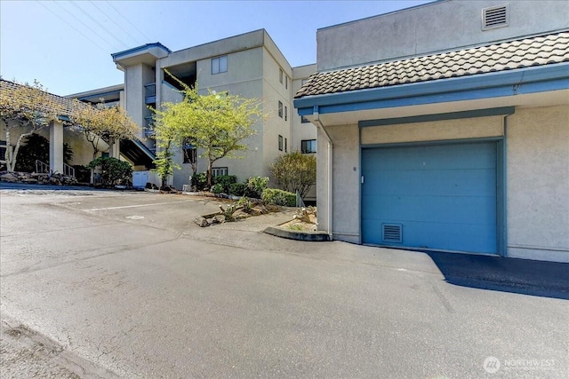 view of front of property with uncovered parking, stucco siding, and a tiled roof