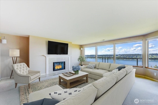 living area with a tile fireplace, baseboards, and light carpet