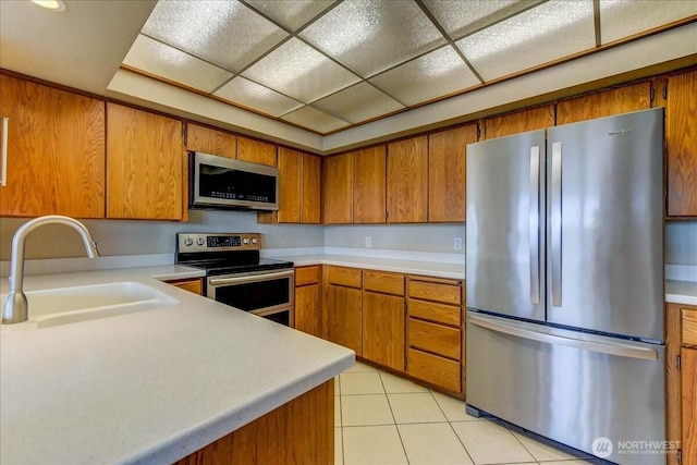 kitchen featuring brown cabinets, stainless steel appliances, light countertops, and a sink
