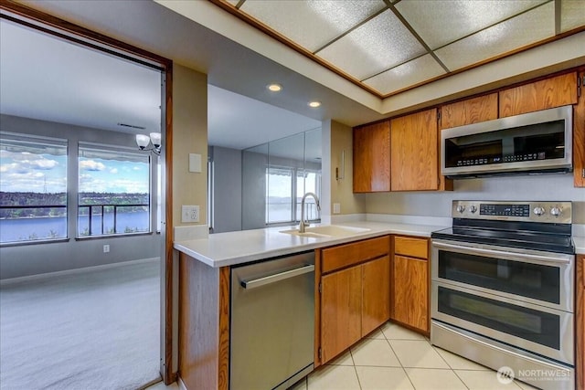 kitchen featuring brown cabinets, stainless steel appliances, light countertops, and a sink