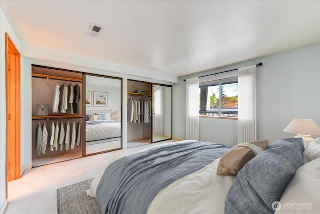 bedroom with carpet flooring, visible vents, and multiple closets