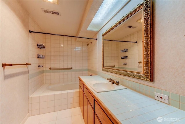 full bath featuring tile patterned floors, visible vents, tiled shower / bath combo, and vanity