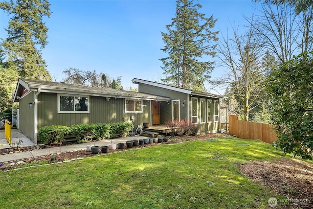 view of front of house featuring a deck, a front yard, and fence