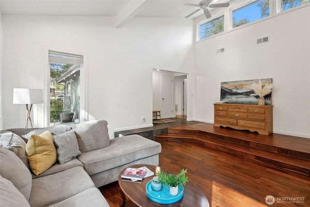 living room featuring a wealth of natural light, beam ceiling, visible vents, and wood finished floors