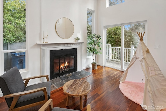 sitting room featuring wood-type flooring and a fireplace with flush hearth