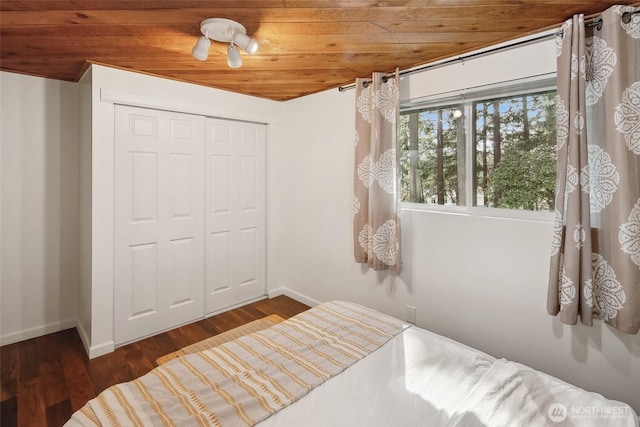 bedroom featuring a closet, wooden ceiling, baseboards, and wood finished floors