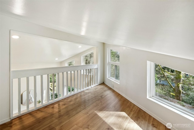 interior space with lofted ceiling, baseboards, wood finished floors, and recessed lighting