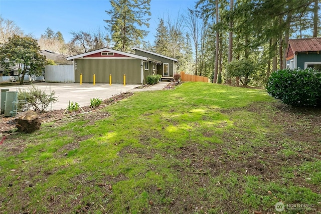 view of yard featuring concrete driveway and fence