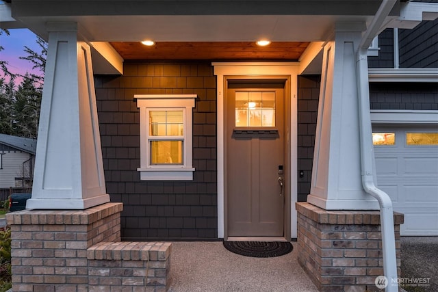 exterior entry at dusk with a porch and a garage