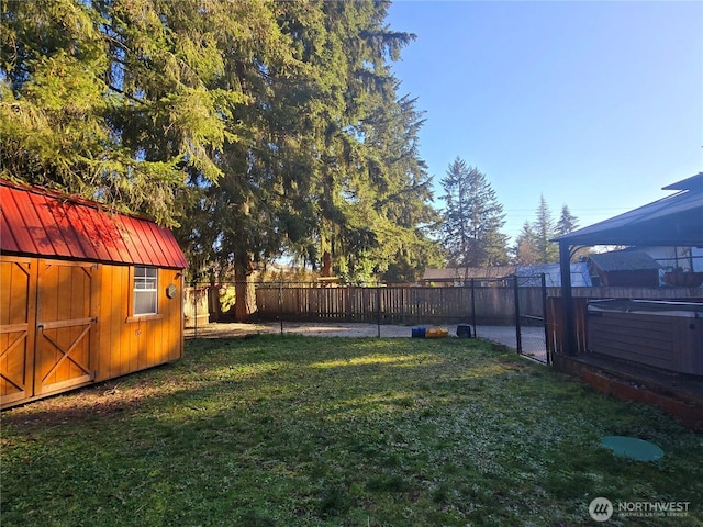 view of yard with a shed, an outdoor structure, a fenced backyard, and a hot tub