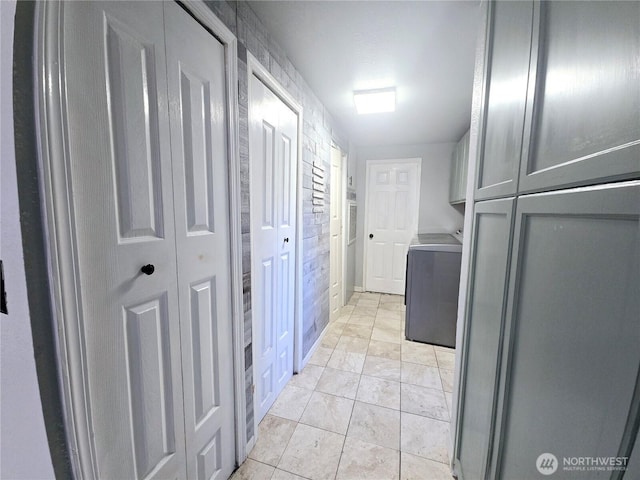 clothes washing area with cabinet space and light tile patterned floors