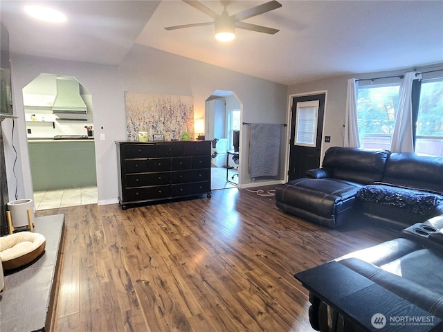 living area featuring lofted ceiling, ceiling fan, arched walkways, and wood finished floors