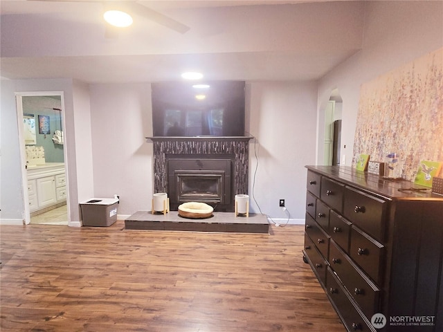 living room featuring a glass covered fireplace, wood finished floors, and baseboards