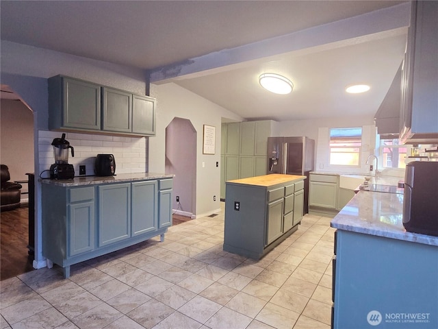 kitchen with arched walkways, a center island, vaulted ceiling with beams, backsplash, and butcher block countertops