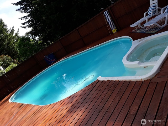 view of pool featuring a wooden deck and a pool with connected hot tub