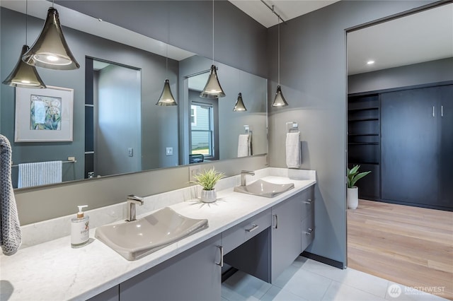 full bath featuring double vanity, a sink, and wood finished floors