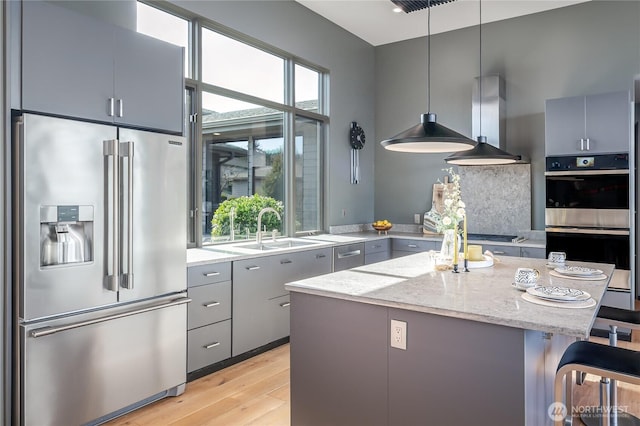 kitchen with a healthy amount of sunlight, stainless steel appliances, range hood, and gray cabinetry