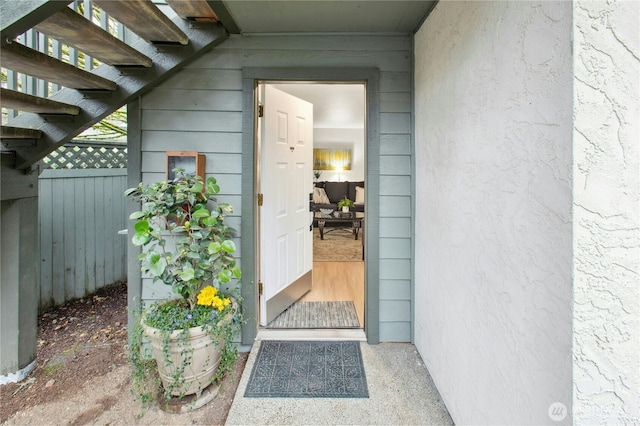 view of exterior entry featuring fence and a pergola