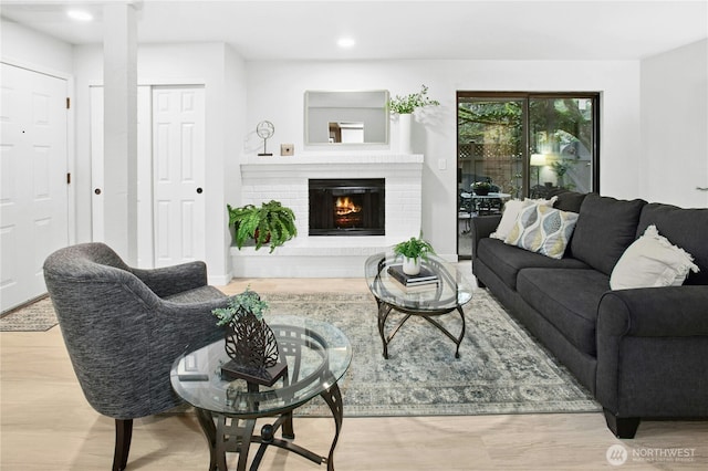 living area featuring recessed lighting, a brick fireplace, and wood finished floors