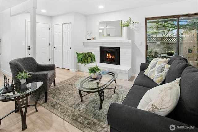 living area with recessed lighting, a brick fireplace, baseboards, and wood finished floors