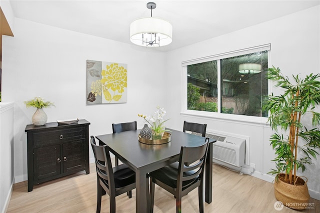 dining space featuring baseboards, an inviting chandelier, a wall mounted AC, and light wood finished floors