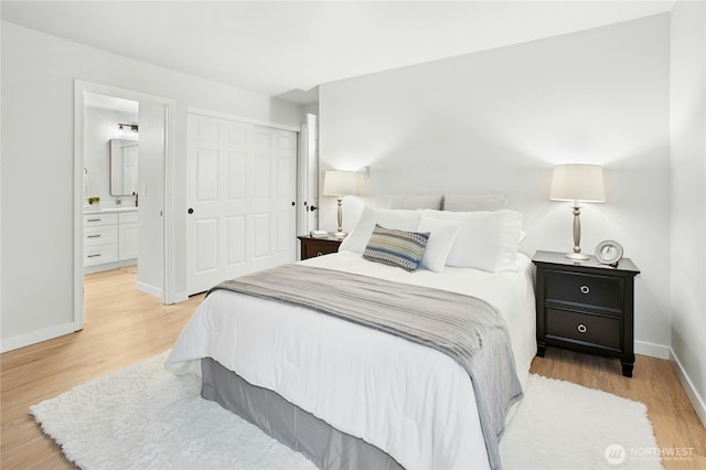 bedroom with light wood-style flooring, a closet, baseboards, and ensuite bathroom