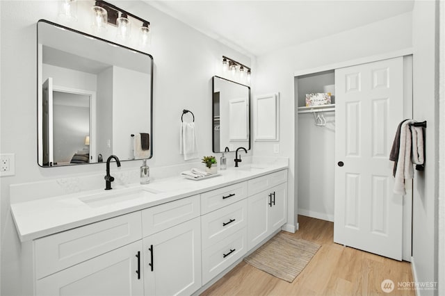 full bath with double vanity, wood finished floors, ensuite bathroom, and a sink