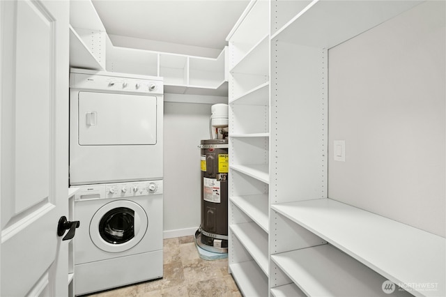 laundry area with laundry area, electric water heater, and stacked washer / drying machine