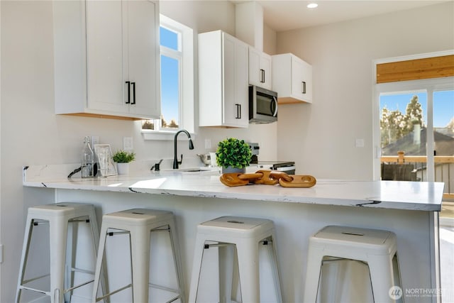 kitchen with stainless steel appliances, a sink, a peninsula, and a kitchen breakfast bar