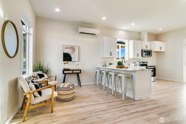 kitchen featuring stainless steel appliances, a wall mounted air conditioner, a wealth of natural light, and a kitchen breakfast bar