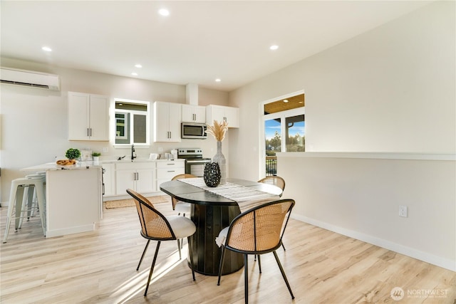 dining area with light wood-style floors, recessed lighting, baseboards, and a wall mounted AC